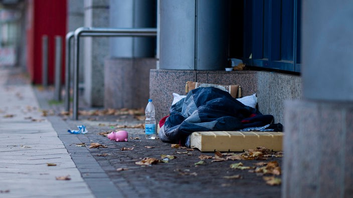 Ein Obdachloser schläft in einer Einkaufsstraße in Dortmund.
