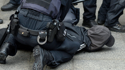 Polizisten fixieren einen Mann auf dem Boden