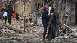 Ukrainische Menschen tragen ihre Habseligkeiten, als sie ihr Haus verlassen, das nach ukrainischen Angaben bei einem russischen Raketenangriff zerstört wurde.