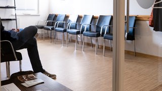 Ein Patient sitzt im Wartezimmer einer Gemeinschaftspraxis.