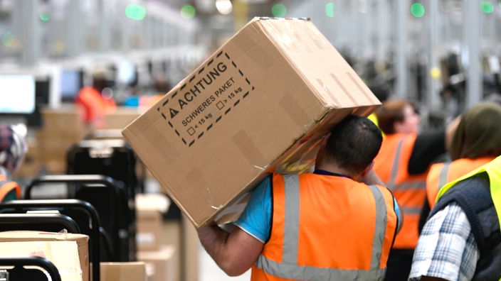 Ein Mitarbeiter trägt ein Paket im Logistikzentrum des Versandhändlers Amazon.