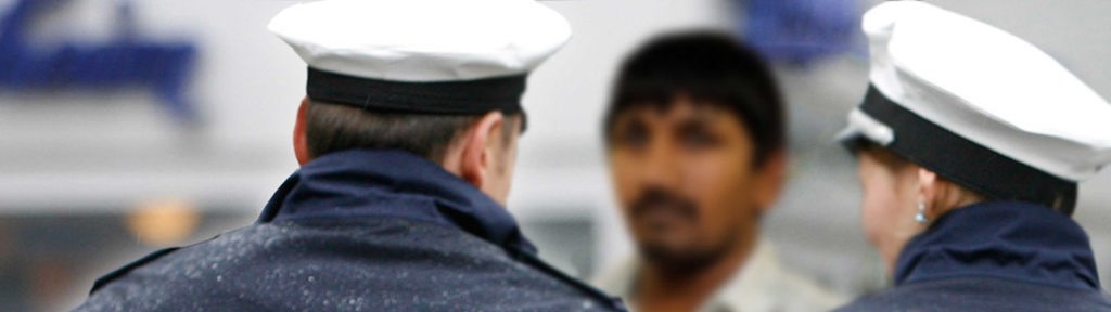 Zwei Polizisten stehen einem Mann mit dunklerer Hautfarbe gegenüber