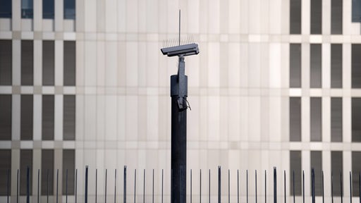 Eine einzelne Überwachungskamera vor einem grauen Gebäude