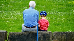 Ein Rentner sitzt mit einem Jungen auf einem Stein