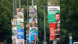 Einige Straßenlaternen, die mit Wahlplakaten behängt sind