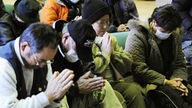 Japaner beten im März 2011 in der Stadt Fukushima