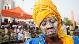 Frau mit Kopftuch und weiß geschminktem Gesicht beim jährlichen Voodoo-Festival in Benin