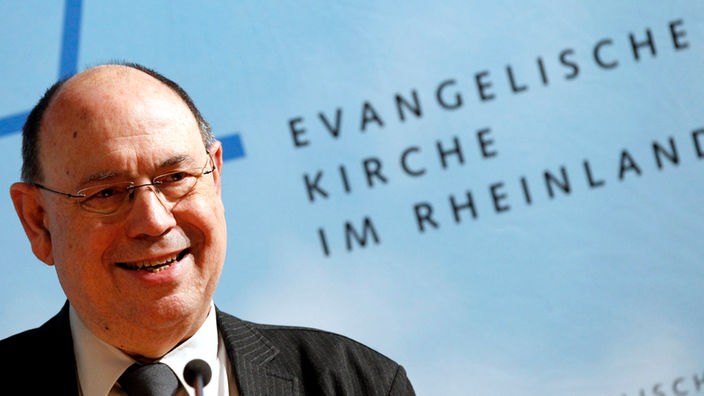 Präses Nikolaus Schneider neben dem Schriftzug 'Evangelische Kirche im Rheinland'