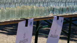 Flaschen mit Wasser aus dem Rhein und Leitungswasser stehen beim Tauffest vom Evangelische Kirchenverband Köln und Region bereit.