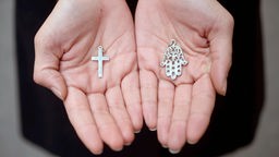 Hände halten Kreuz und Hand der Fatima