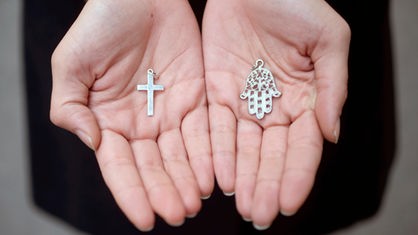 Hände halten Kreuz und Hand der Fatima