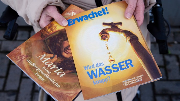 Hände halten die Zeitschriften "Wachturm" und "Erwachet"