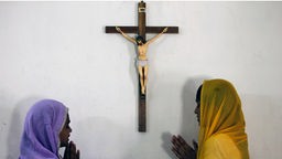 Zwei indische Frauen beten vor Kruzifix