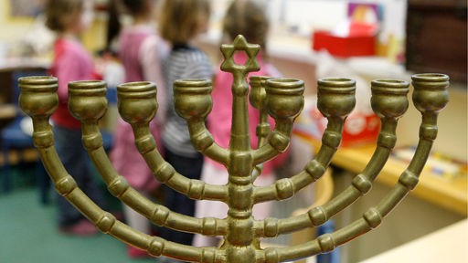 Neunarmiger Leuchter (Chanukkia), im Hintergrund spielende Kinder