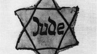 Eine schwarz-weiß Aufnahme eines Davidsterns mit der Aufschrift "Jude"