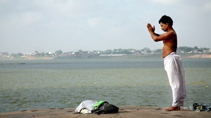 An Mann steht am Ganges und betet