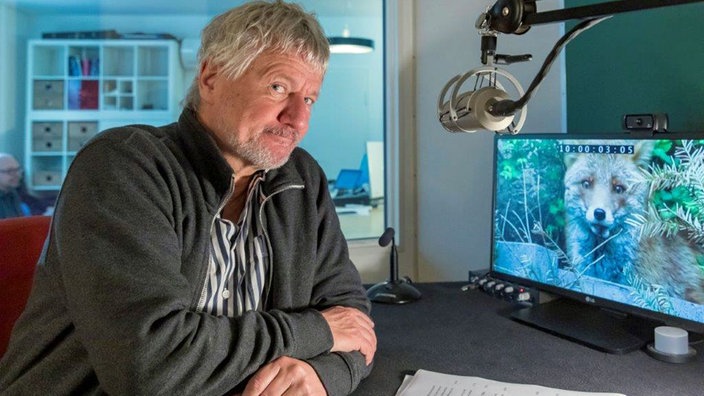 Der Kabarettist Jürgen Becker sitz am Schnittplatz, auf dem Monitor ist ein Fuchs zu sehen.