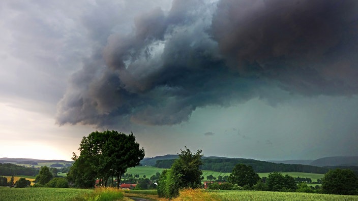 Eine gigantische Sturmwolke baut sich über dem Land auf.