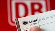 Bahn-Fahrkarte, im Hintergrund das Logo der Deutschen Bahn