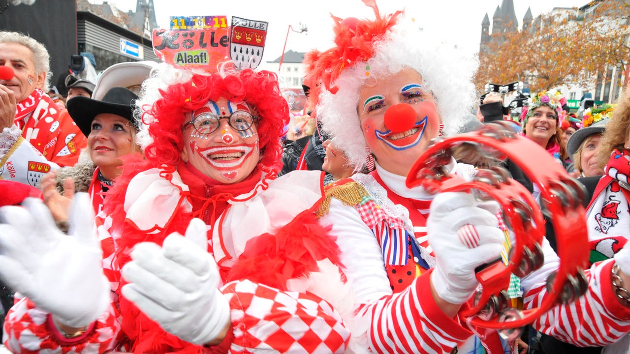 Viele bunt verkleidete menschen, die in einer Straße Karneval feiern