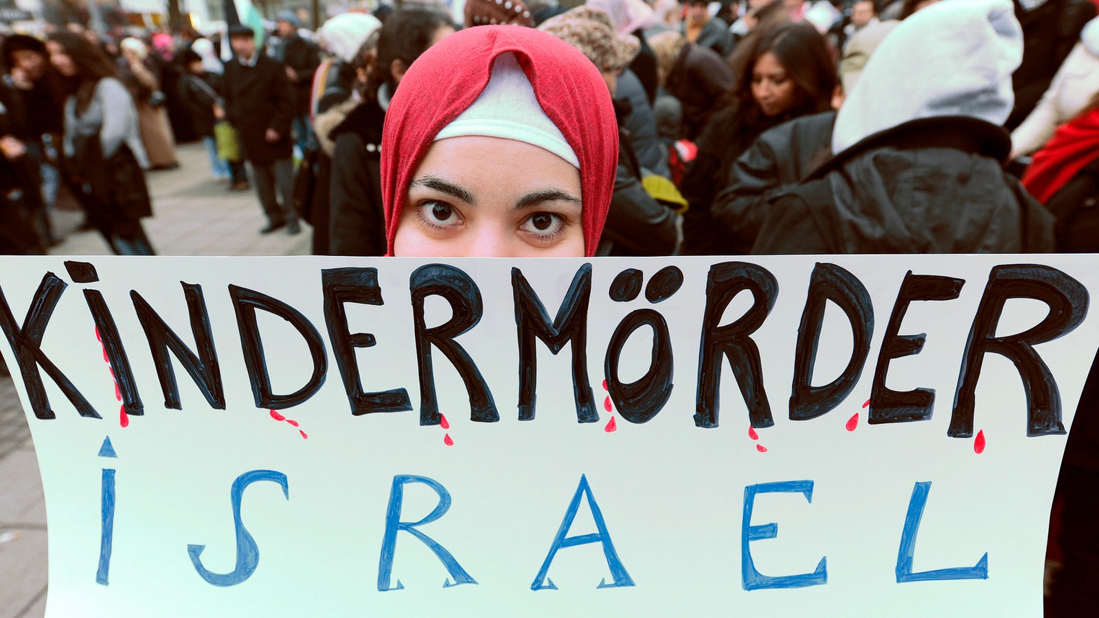 Frau mit Plakat "Kindermörder Israel"