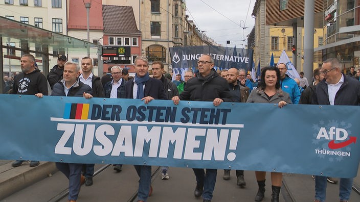 Björn Höcke ahält auf einer Demonstration ein Banner