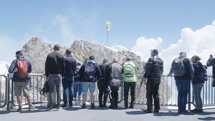 Menschen stehen vor dem Gipfelkreuz