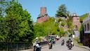 Motorradfahrer vor einer Burg.