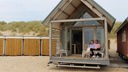 Ein Paar sitzt händchenhaltend auf der Terasse eines Strandhauses. 