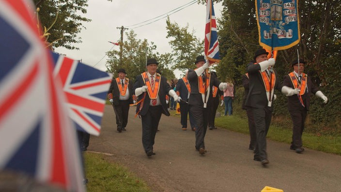 Mehrere Männer, im Vordergrund die britische Flagge