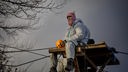 Aktivist sitzt auf Hochsitz, dämmriger Himmel