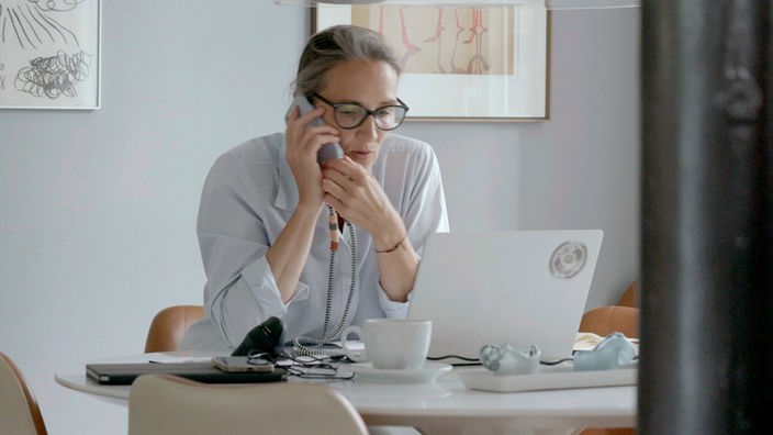 Eine Frau schaut auf einen Laptop und telefoniert.
