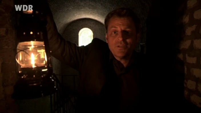 Mann mit einer Lampe in einem Kellergewölbe 
