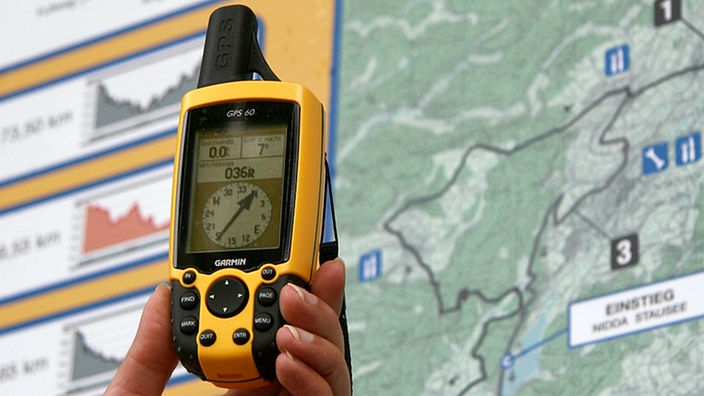 Ein GPS-Empfänger für Geocoaching vor einer Wandertafel