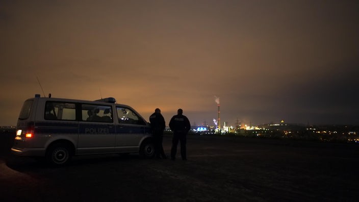 Schattenbild zweier Männer bei Nacht vor einer erleuchteten Stadt