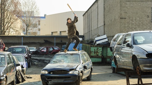 Peter Faber (Jörg Hartmann) schlägt mit einem Baseballschläger auf ein Auto ein.