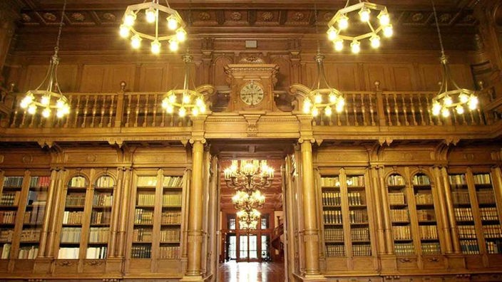 Ein pompöser Raum mit Bücherregalen im Hintergrund und einer Tür in der Mitte