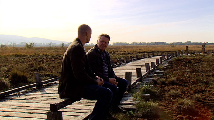 Christian Dassel sitzt mit Musiker Richie Arndt an einem Trampelpfad