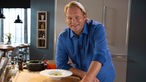Björn Freitag im WDR-Kochstudio mit einem Teller Kohlrabisuppe. 