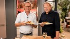 Frank Buchholz und Björn Freitag halten Teller mit Wiener Schnitzel in der Hand.