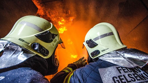Zwei Feuerwehrmänner vor einem Brandherd