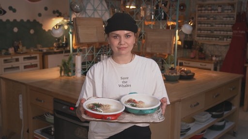 Foodbloggerin präsentiert stolz ihr fertig zubereitetes Essen auf einem Tablett 