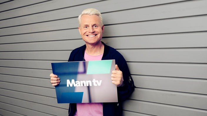 Mann hält Schild mit Mann tv Logo in der Hand