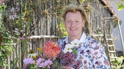Floristmeister Björn Kroner inmitten von Blumen. 