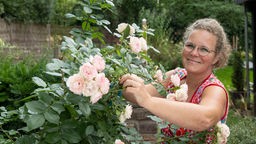 Kai Judith Wetzel bei einem Rosenstrauch in ihrem Garten.