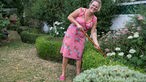 Kai Judith Wetzel mit einem Rechen in ihrem Garten. 