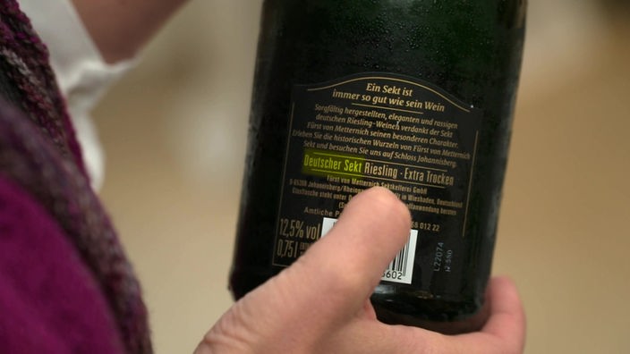 Das Bild zeigt die Rückseite einer Flasche Sekt. Ein Finger deutet auf den Herkunftsort.