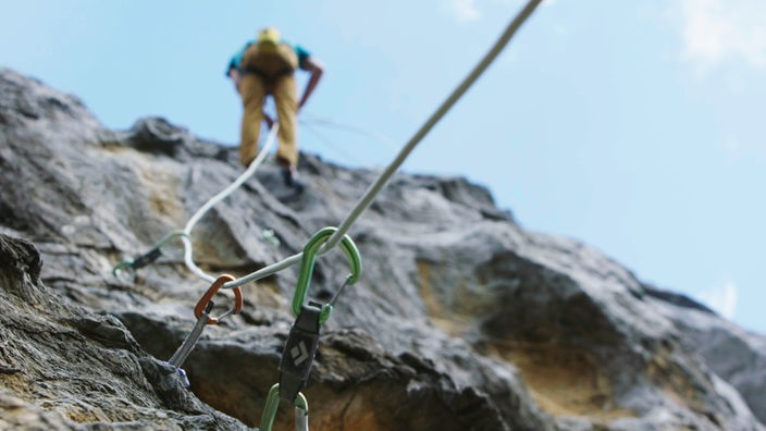 Bergsteiger mit Karabinerhaken im Vordergrund