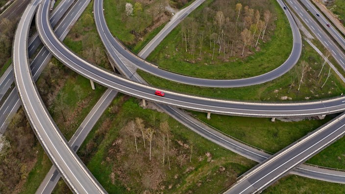 Luftaufnahme von einem Autobahnkreuz, auf dem nur ein rotes Auto zu sehen ist