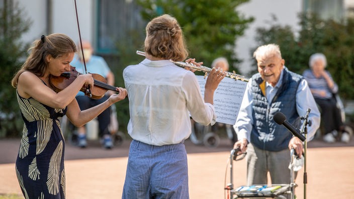 Zwei Frauen musizieren für Senioren im Hof